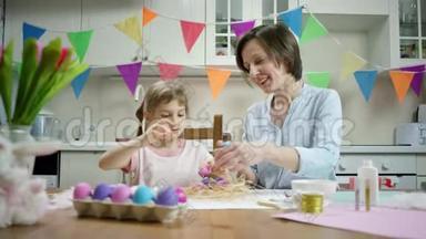 母女俩坐在餐桌前，一起用彩蛋装饰鸟巢，一起在厨房里笑